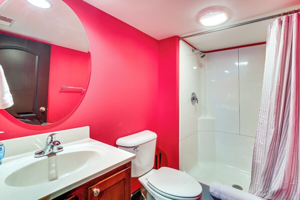 A bathroom with a red wall, white sink, and toilet. - Bar, Pool Table & Yard! Spacious Union Home (Union)