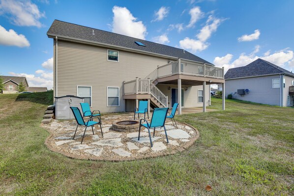 A two-story house with a covered patio area featuring four blue chairs and a fire pit. - Bar, Pool Table & Yard! Spacious Union Home (Union)