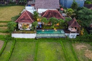 A large house with a swimming pool, surrounded by lush greenery and fields. - Umah Sunset (Bali)