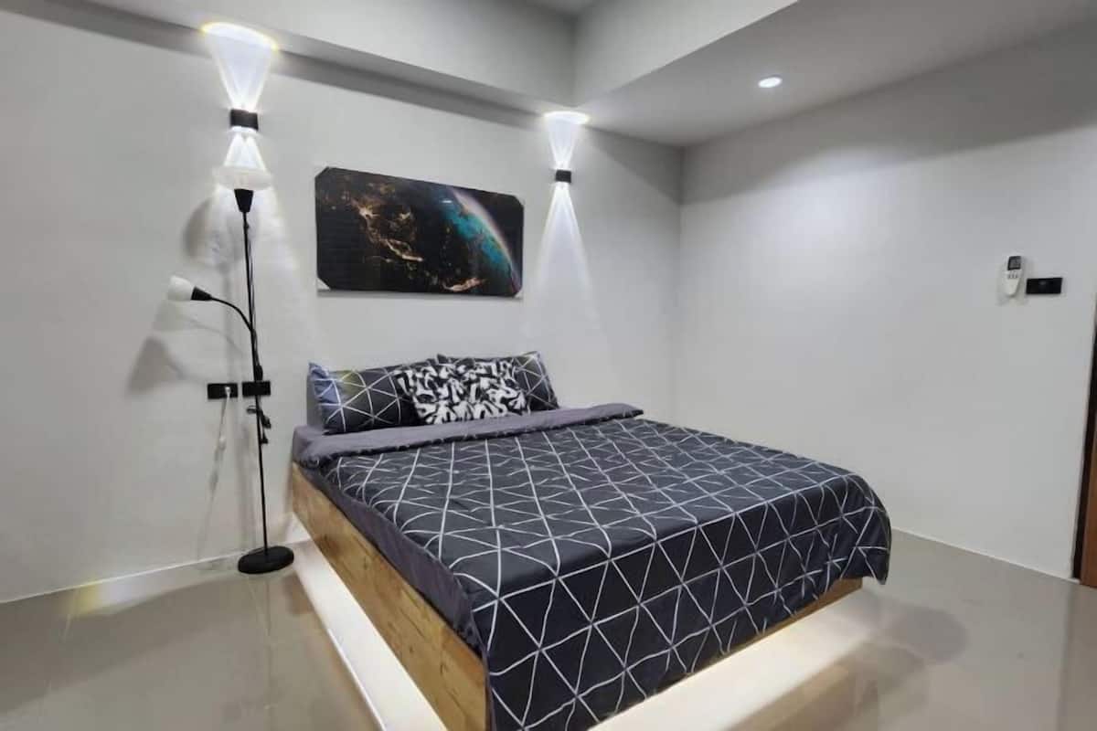 Un dormitorio moderno con una cama, dos lámparas de pared y un cuadro.