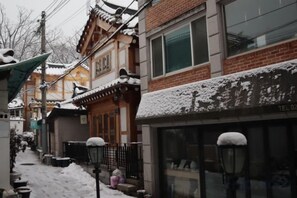 Un edificio tradicional con techo nevado y escaparate visible.