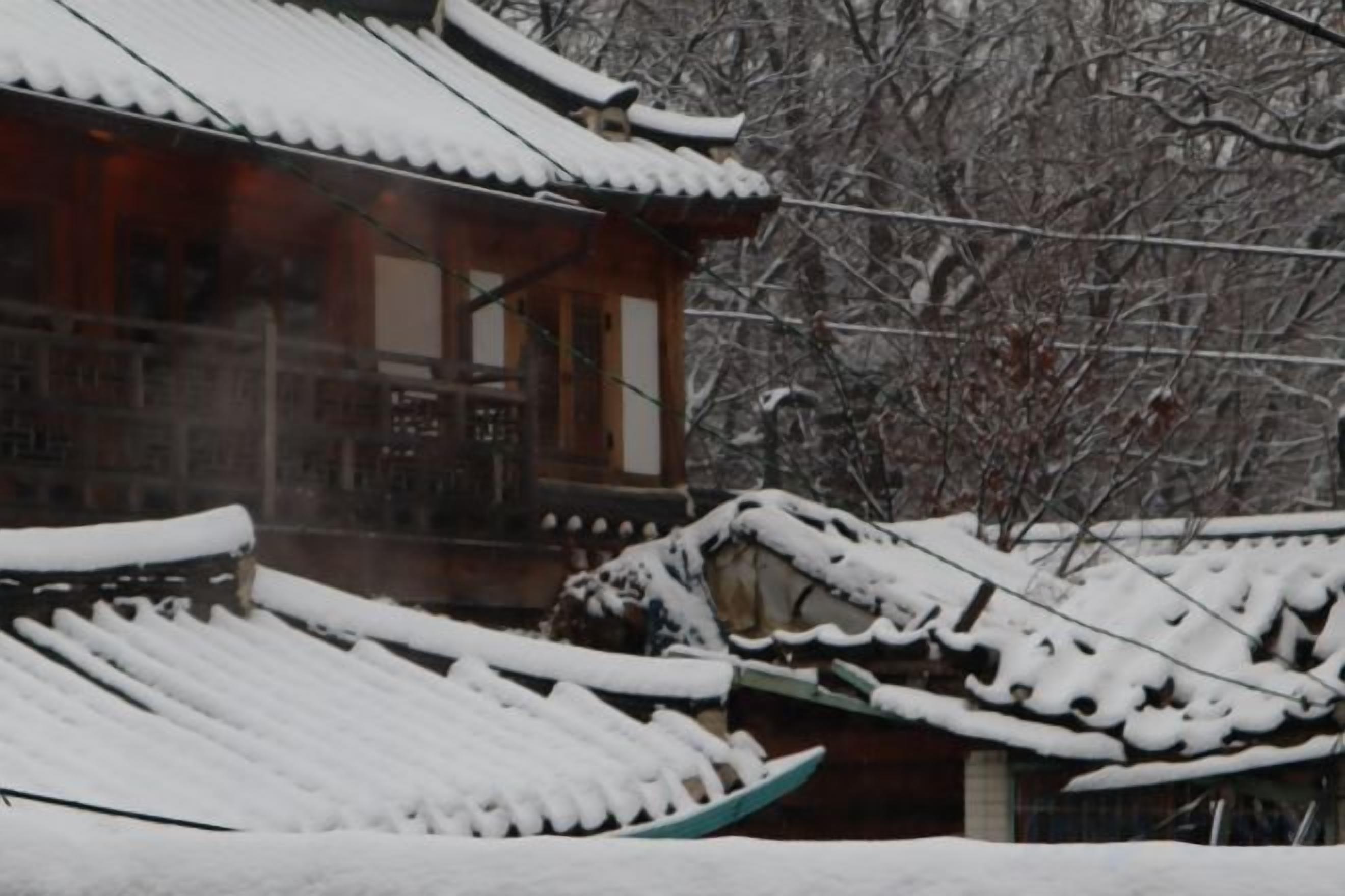 A traditional building with snow-covered roofs and a wooden structure.
