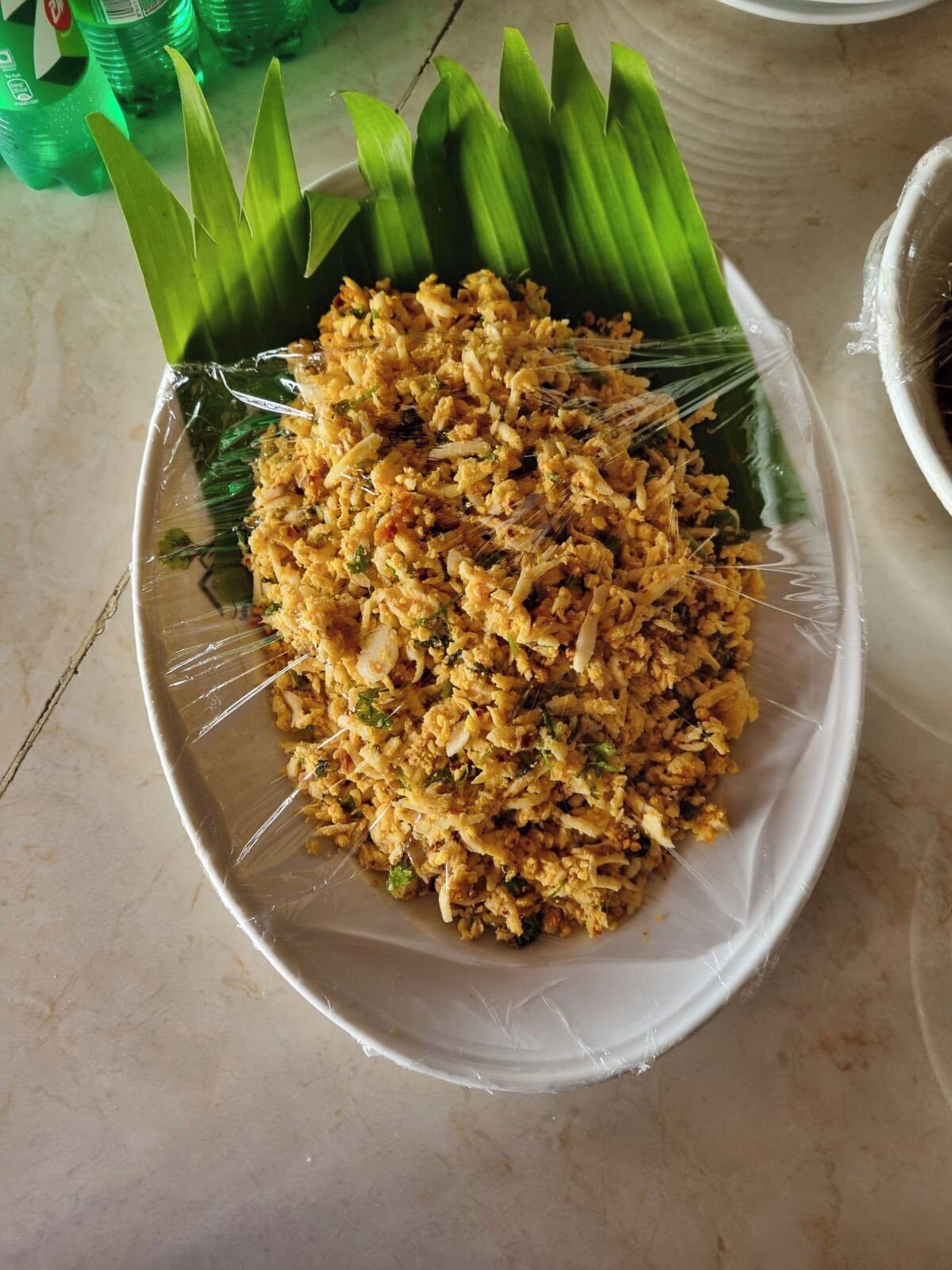 A plate of fried rice garnished with green leaves, possibly banana leaves, on a white plate.