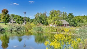 Un cadre paisible au bord d’un lac, avec un moulin, des bâtiments rustiques et une végétation luxuriante.
