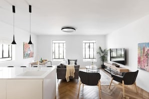 A modern living room with a sofa, TV, and dining area.