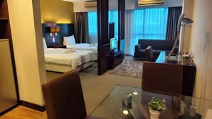A hotel room with a bed, a sofa, a TV, a desk, and a glass table with a plant. - South China Sea Place Suites by Kinabina Homestay (Kota Kinabalu)