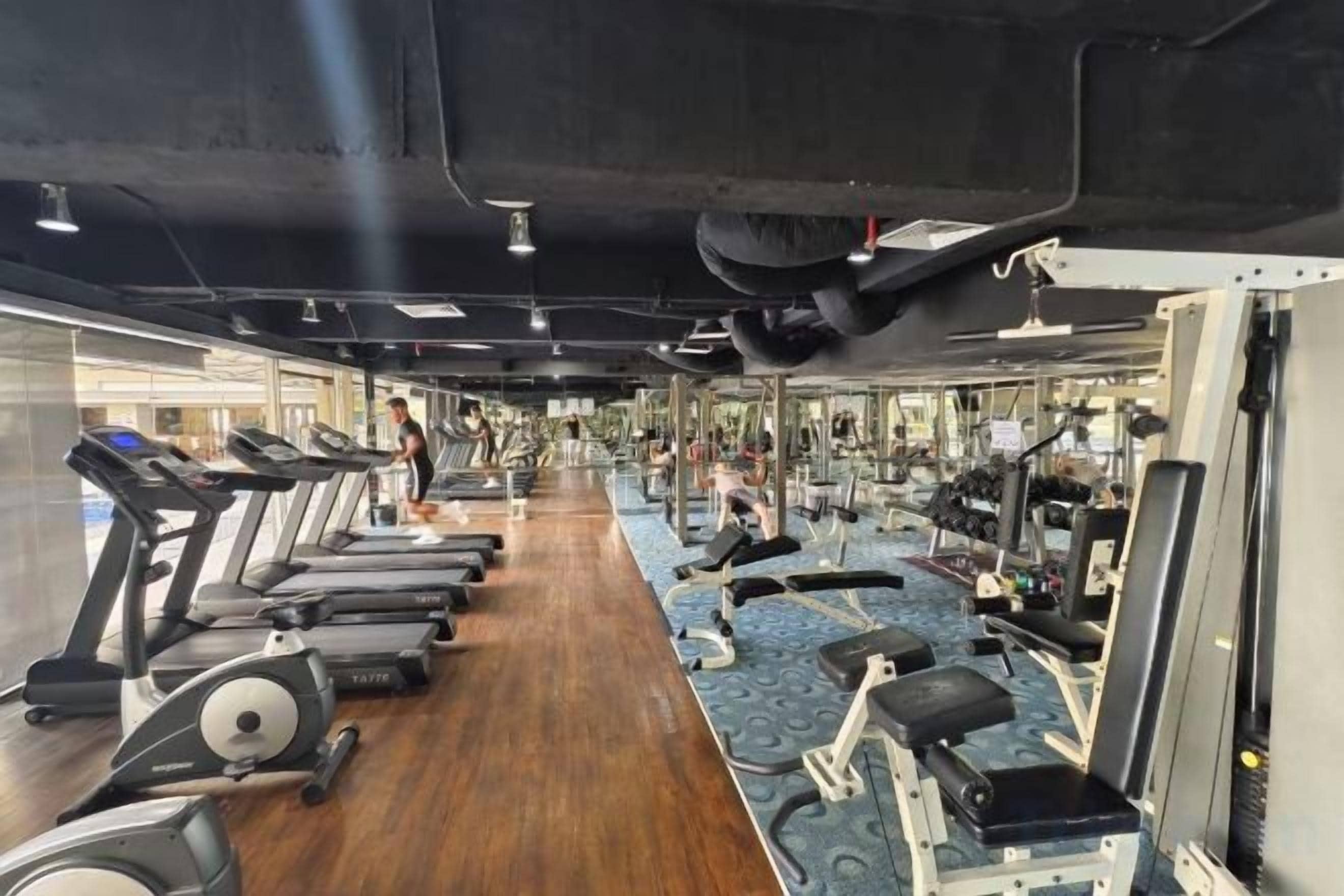 Un gimnasio con cintas de correr, bicicletas estáticas y máquinas de pesas.