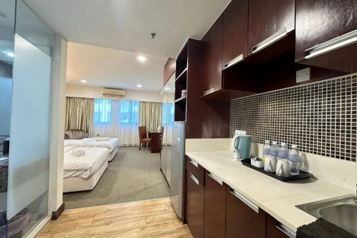 A hotel room with a kitchenette, a bed, a desk, and a view of the outside.