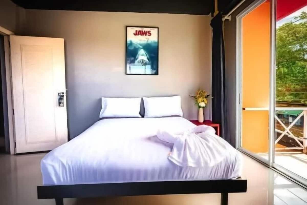 Une chambre à coucher avec un lit, une affiche au mur, une fenêtre et une porte.
