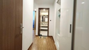 Ein Korridor mit Holzboden, einer Tür links und einem durchgegangenen Badezimmer in der Mitte.