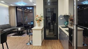 Ein modernes Wohnzimmer mit Sofa, Couchtisch und Sesseln. Es gibt eine Küchenzeile mit Spüle und Schränken.
