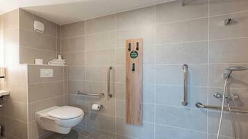 Un baño moderno con inodoro, ducha con barras de apoyo y un perchero para toallas.