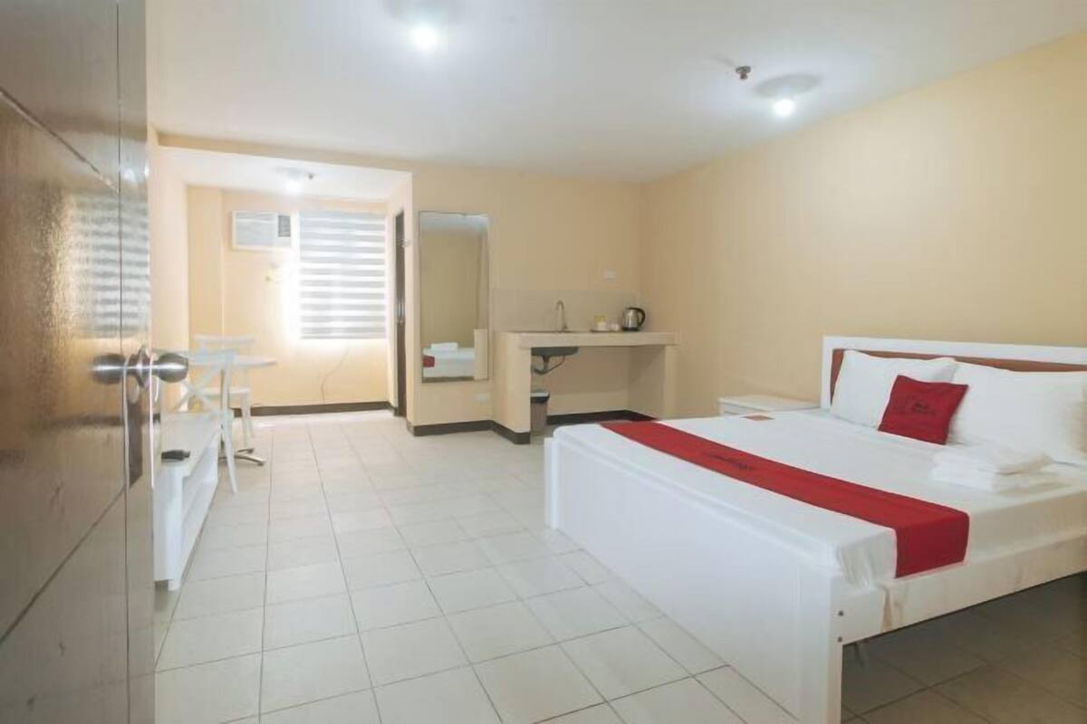 Habitació d'hotel amb llit, escriptori, cadira, mirall i finestra.