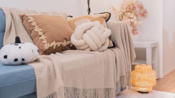 A cozy room with a blue sofa, a white lamp, and a decorative plant. - New Garfieldhome Shinjuku (Tokyo)