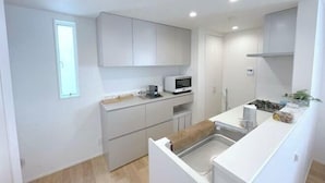 A compact kitchen with white cabinets, a microwave, and a sink. - New Garfieldhome Shinjuku (Tokyo)