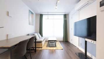 A modern living room with a sofa, dining table, and TV.