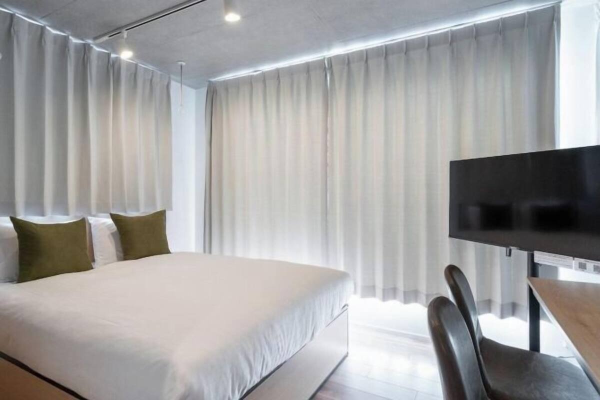 Una camera d'albergo con un letto, una televisione, una scrivania e tende.