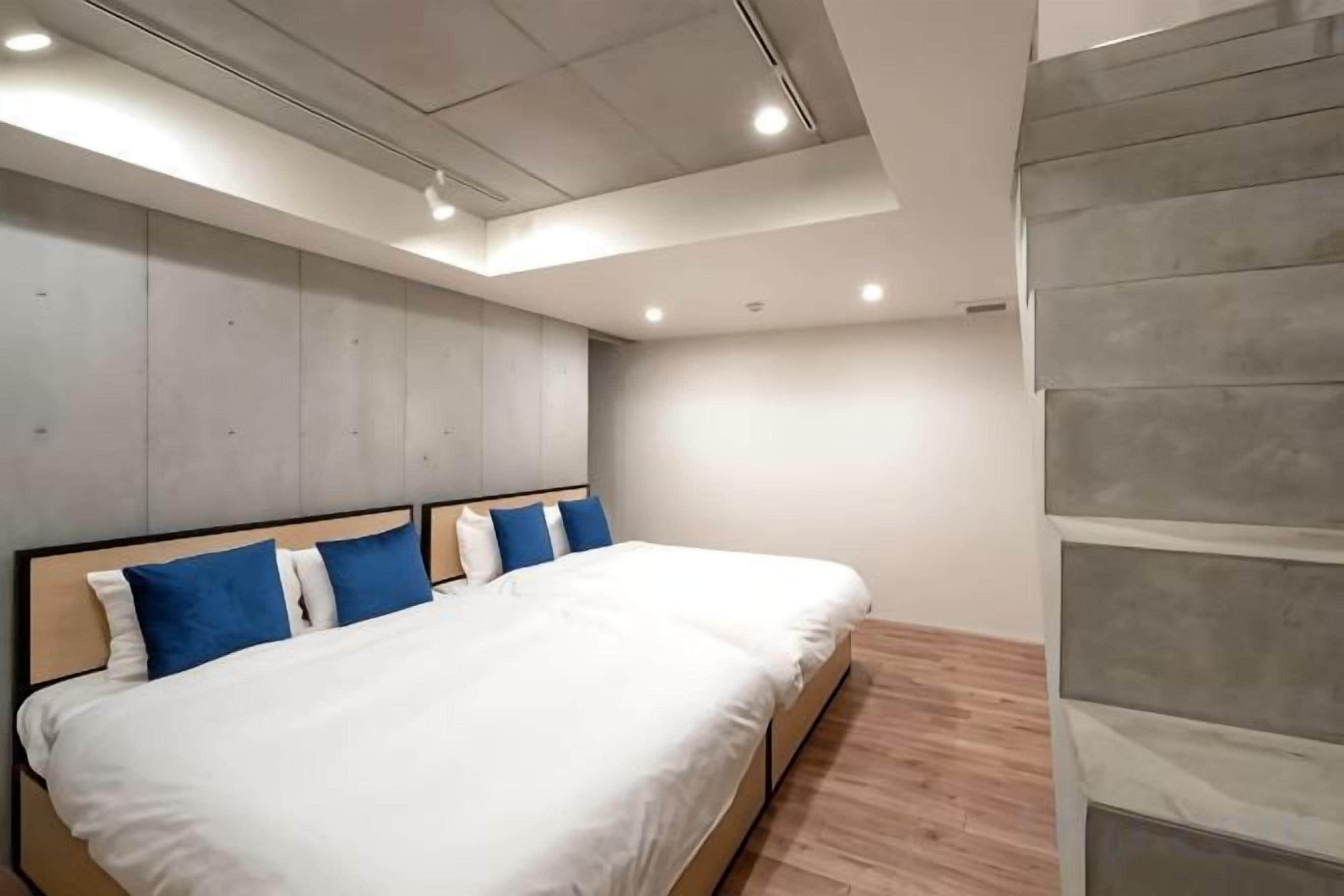 Una camera da letto moderna con un letto grande, un pavimento in legno e una parete grigia.