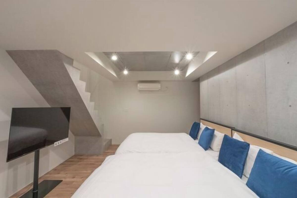 Una camera da letto con un letto, una televisione, una scala e un condizionatore d'aria.
