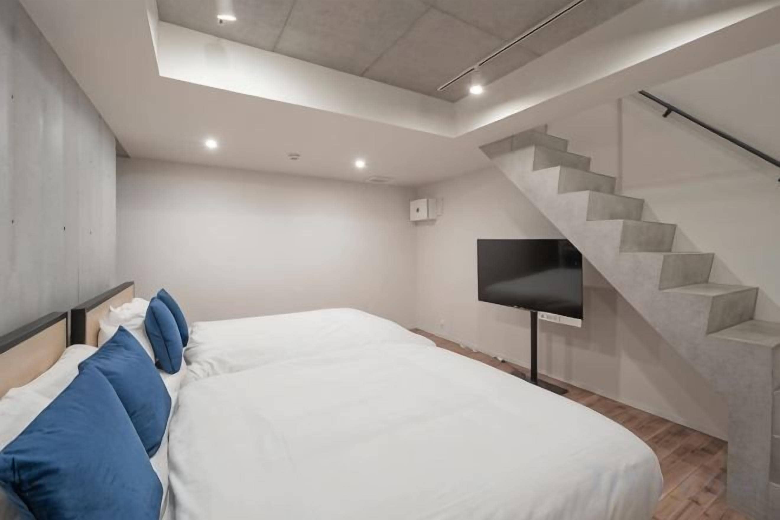 Une chambre moderne avec un grand lit, un téléviseur à écran plat et un escalier.