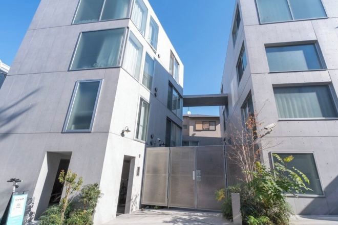 Un edificio moderno con un patio central, ventanas amplias y una verja de metal.