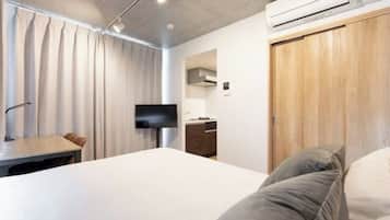 Una habitación de hotel moderna con cama, escritorio, televisor y armario de madera.