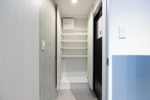 Un couloir étroit doté d’une étagère intégrée et d’une porte située sur le côté droit.