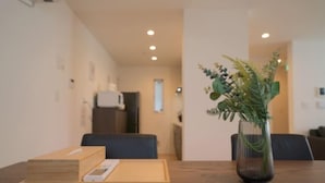 Een houten tafel met een dienblad, een vaas met groene planten, en een kamer met een donkergroene bank en een witte muur.