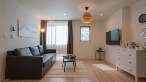 Een moderne woonkamer met een bank, een salontafel, een televisie en een kast.