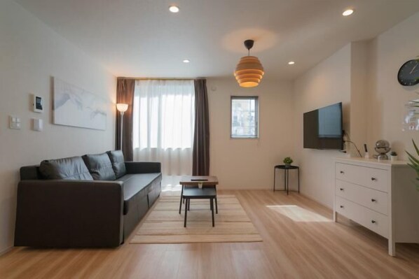 A modern living room with a sofa, a small table, a TV, and a cabinet.