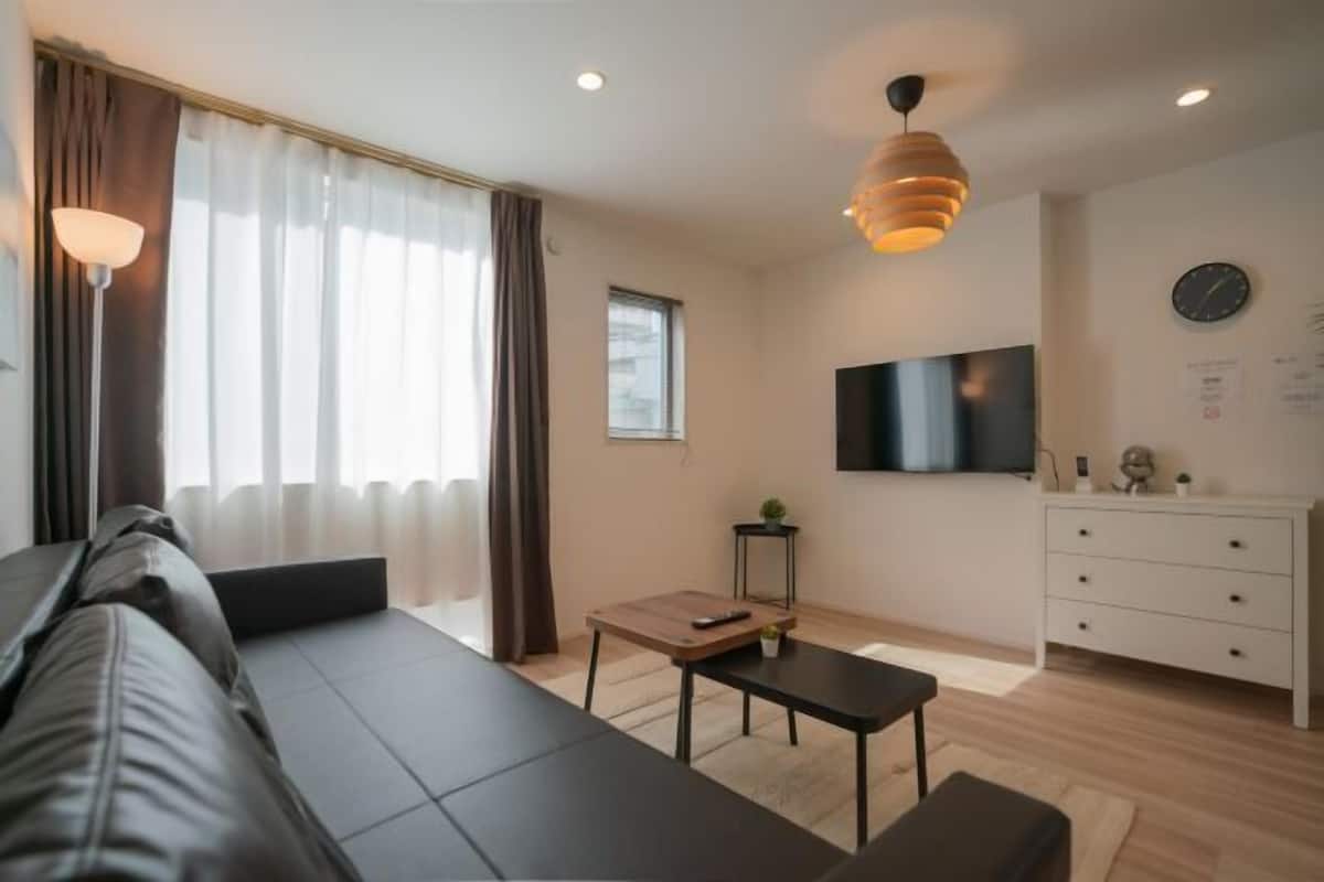 Een moderne woonkamer met een bank, een salontafel, een televisie, een bijzettafeltje en een kast.