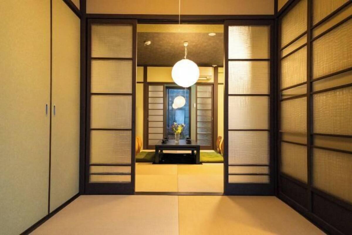 A traditional Japanese room with tatami flooring, sliding doors, and a hanging light fixture.