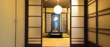 A traditional Japanese room with tatami flooring, sliding doors, and a hanging light fixture.