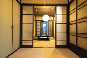 Une pièce de style japonais traditionnel, avec un sol recouvert de tatamis, des portes coulissantes et un luminaire suspendu.