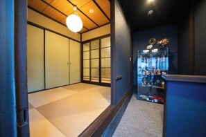 A traditional Japanese interior with tatami flooring, sliding doors, and a modern glass display case.