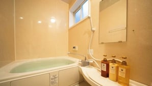 A bathroom with a bathtub, a sink, and a mirror. There are three bottles of soap on the sink. - KIRAKU･LITTLE HOME (Kyoto)