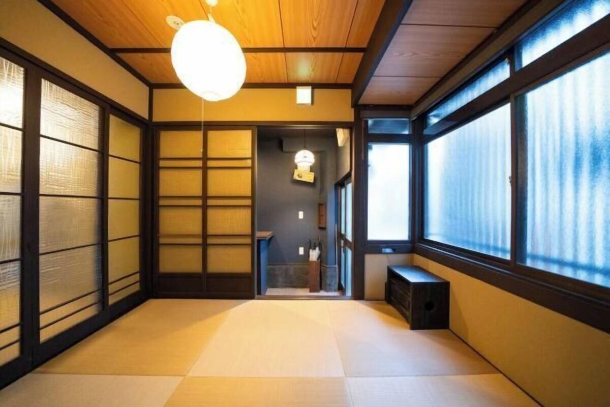 Una habitación japonesa tradicional con suelo de tatami, puertas correderas y un ventanal grande.