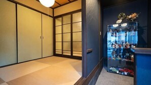 A traditional Japanese room with tatami flooring, sliding doors, and a display case with various items. - KIRAKU･LITTLE HOME (Kyoto)