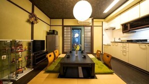 A compact living space with a dining table, chairs, a TV, and a kitchen area. - KIRAKU･LITTLE HOME (Kyoto)