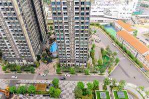Un immeuble résidentiel de grande hauteur, doté de nombreux balcons, d’une cour intérieure et entouré d’un environnement urbain.
