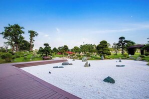 A serene garden with a wooden deck, neatly arranged rocks, and various trees. - THE LANDMARK 81 LUXURY ART CONDOTEL (Ho Chi Minh City)