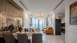 Un comedor moderno con una mesa preparada para cuatro personas, un sofá al fondo y un ventanal con vistas a la ciudad.