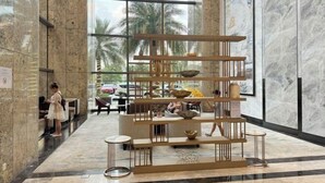 Un vestíbulo con diseño moderno y abierto, que presenta una estructura central de madera con cuencos y una zona de estar.