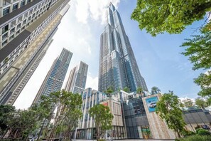 Un moderno edificio de gran altura con fachada de vidrio, rodeado de palmeras y otra vegetación.