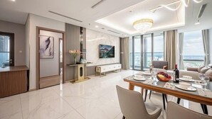 Un comedor moderno con una mesa grande dispuesta para cuatro personas, un televisor montado en la pared y vistas de la ciudad a través de amplios ventanales.