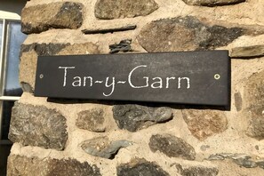 Un muro de piedra con un letrero negro que dice 'Tan-y-Garn'.