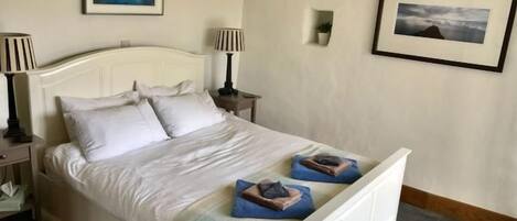 A neatly made bed with pillows, two bedside lamps, and a framed picture on the wall.
