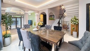 A dining area with a large wooden table, multiple chairs, and a chandelier. - KN3 Holiday Villa (Ho Chi Minh City)