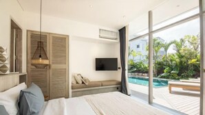 Ein Schlafzimmer mit einem großen Bett, einem Fernseher, einem Fenster mit Blick auf einen Swimmingpool und Grünflächen sowie einem Deckenventilator.