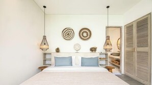 Ein Schlafzimmer mit einem Bett, zwei Pendelleuchten, einer Wand mit Dekotellern und einem Kleiderschrank.
